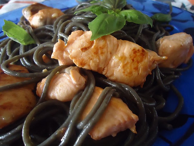cubos de salmão dourados envolvidos em espaghetti nero di sepia perfumados com mangericão